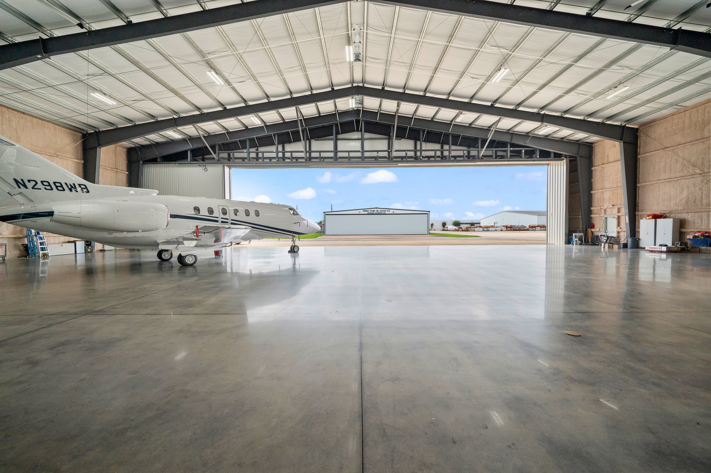 Hangar interior with a jet parked and the door open to the airfield.