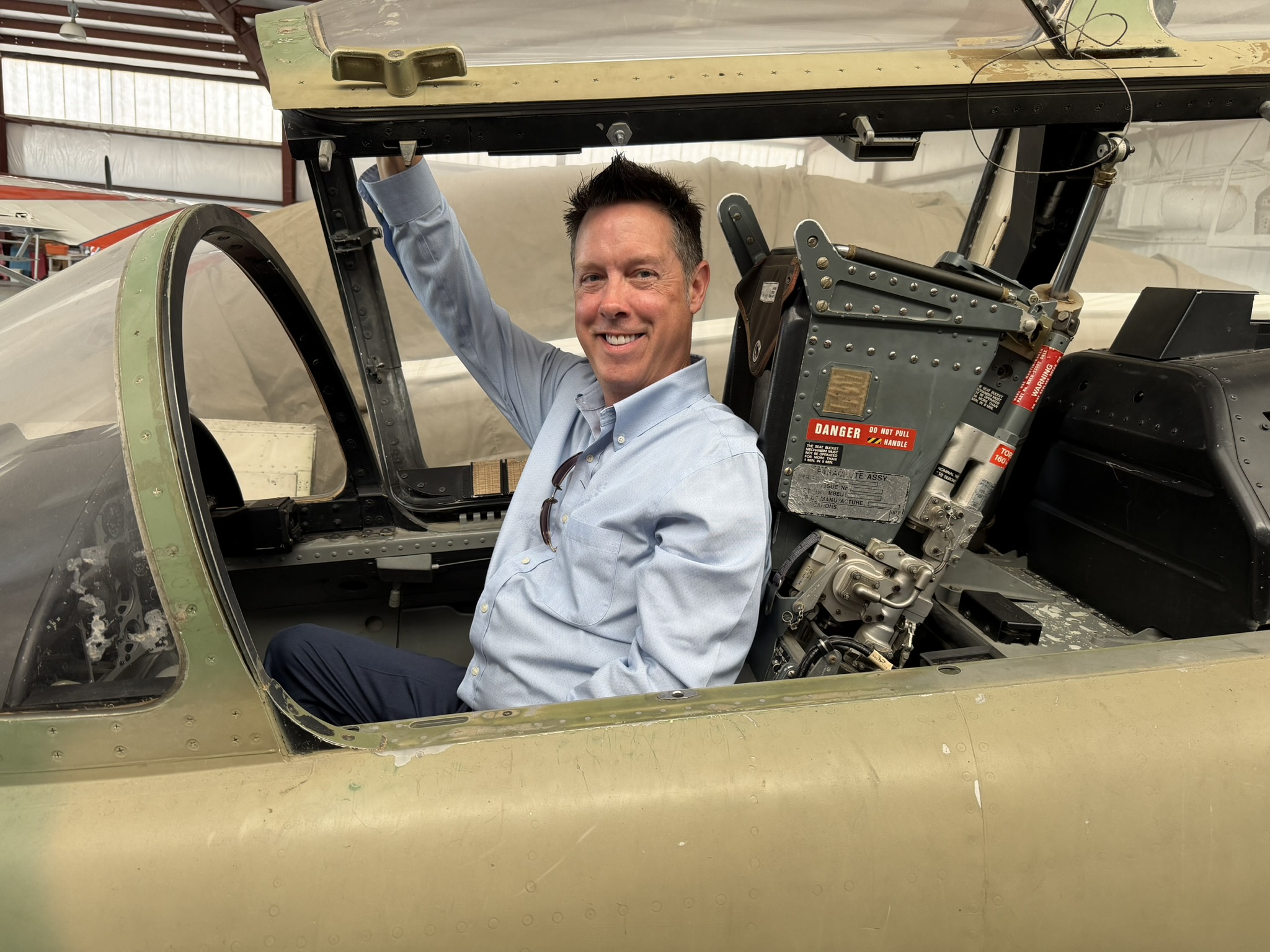 Robert Johnson in the cockpit of a jet inside a hangar.